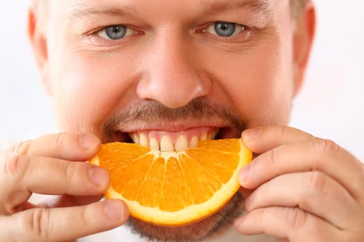 Portrait of smiling man with slice of juicy orange. Vitamins antioxidants in citrus fruits