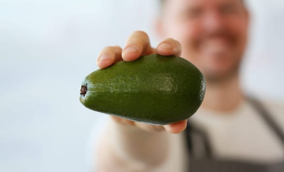 Cook holds fresh juicy green avocado in hands. Natural fresh organic exotic fruits and healthy food