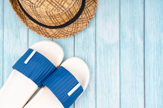 Blue sandals and straw hat with copy-space on blue wooden background.