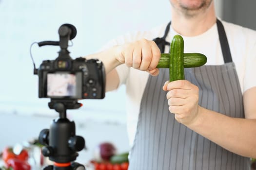 Male cook blog holding two cucumbers in front of camera. Useful video blog about proper nutrition and cooking