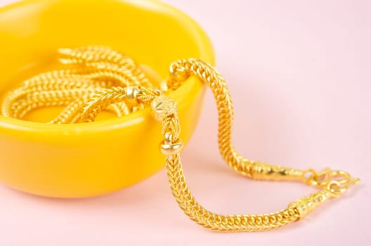 Gold necklace on pink background.