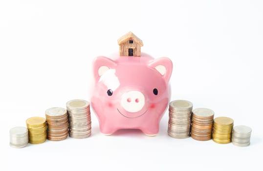 Money coins tower and pink piggy bank on white background.