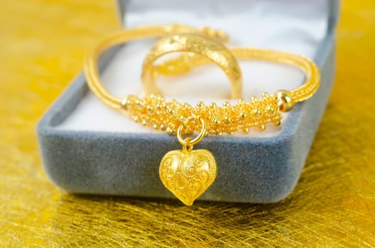 Gold necklace and heart shape pendant with ring on blue velvet box.