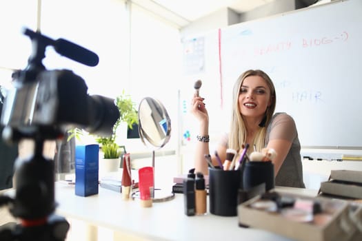 Beautiful woman blogger shows how to apply makeup and use cosmetics. On camera to record beauty vlogs live at home