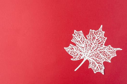 Carve of white paper maple leaves on a red background.