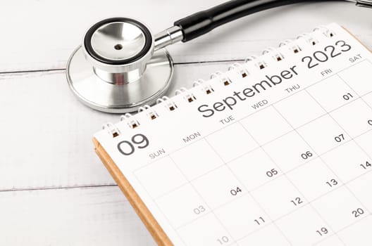 Stethoscope medical and September 2023 desk calendar on wooden background, schedule to check up healthy concepts.