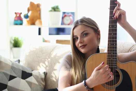 Talented purposeful young woman holds guitar in hands. Woman Practicing playing musical chords improving creative skills concept