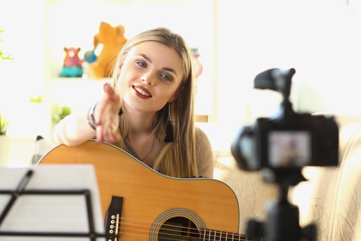Female musician recording guitar teaching videos. Singing and playing female blogger on guitar in front of camera