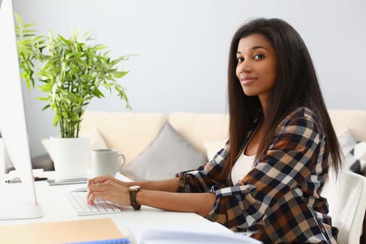 Portrait of happy black business woman at desk typing on computer. Remote work training and information search on Internet