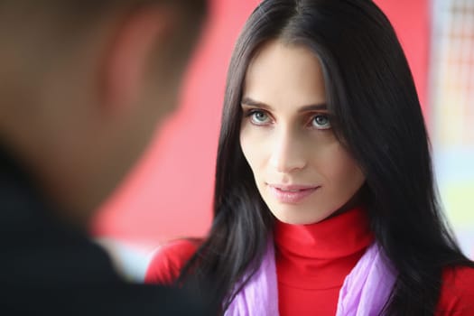 Young woman confidently looks at man. Focused emotions and look of successful woman