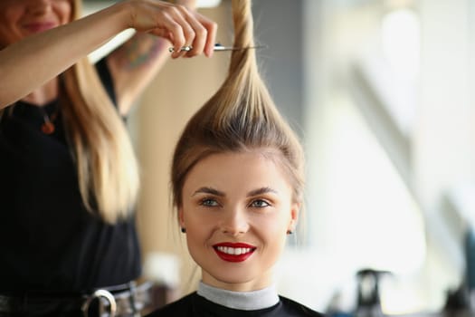 Hairdresser hands cut off blonde tail closeup. Woman hairdresser cutting long blond hair with scissors in barbershop