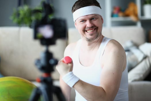 Smiling happy sports blogger blogging about exercises with dumbbells. Remote fitness training and healthy lifestyle concept