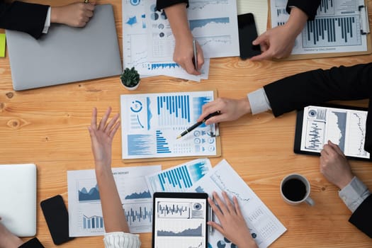 Top-view closeup business team of financial data analysis meeting with business intelligence, report paper and dashboard on laptop. Business group people working together in harmony office.