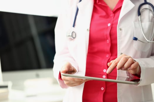 Doctor using tablet computer and medical application in clinic looks at patient diagnosis. Medicine healthcare and insurance