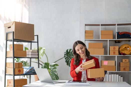 girl working with laptop Online e-commerce at her store. A young woman prepares a parcel box to send to the customer. e-commerce online sales.