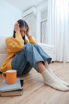 Close up of frustrated ill woman sit floor suffer headache migraine pain have health problems close eyes in house living room.