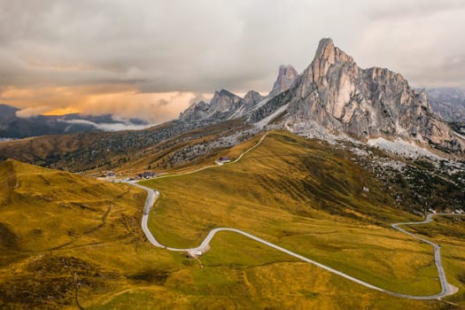 Pathway from Snake Road to high mountain range illuminated by bright sunlight. Small mountain resort for tourists located in Giau Pass