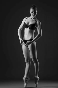 Black and white image of graceful slim ballerina posing in studio