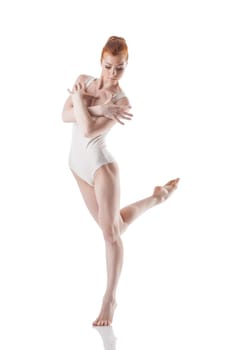 Beautiful red-haired ballerina dancing in studio, isolated on white