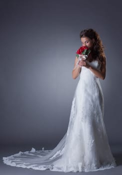 Happy bride posing in chic trendy dress, on gray background