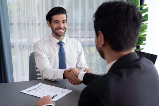 Successful job interview at business office with handshake. Positive discussion of qualifications and application for position. Job hiring concept between candidate and interviewer. Fervent