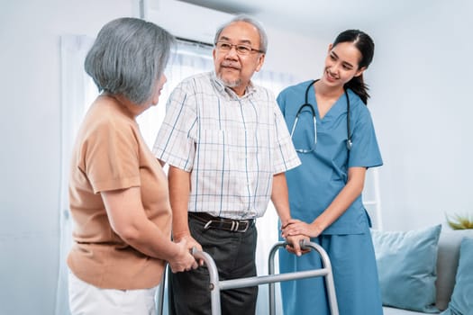 Contented senior man was helped on folding walking by his wife and caregiver. Recuperation for elderly, seniors care, nursing home.