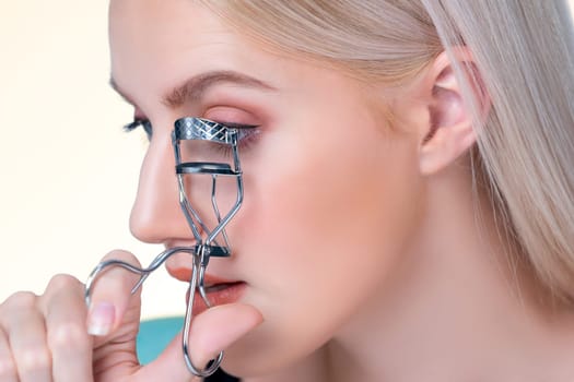 Closeup natural soft facial makeup beautiful personable woman with perfect smooth cosmetic clean skin correct eyelash curler with metal mechanic beauty accessory in isolated background.
