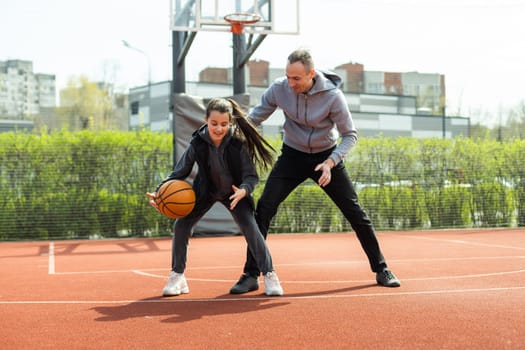 Happy father and teen daughter outside at basketball court