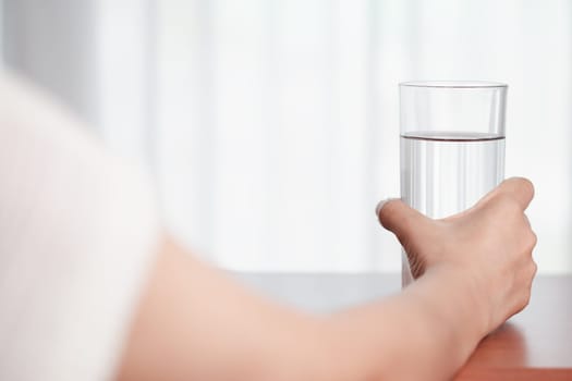 Asian woman's hand holding glass of drinking water for drinking and beverages concept.