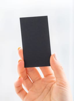 Hand with black blank business card on white background