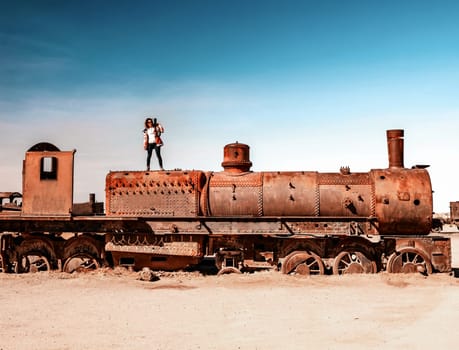 Girl on rusty steam train near Uyuni in Bolivia. Cemetery trains.