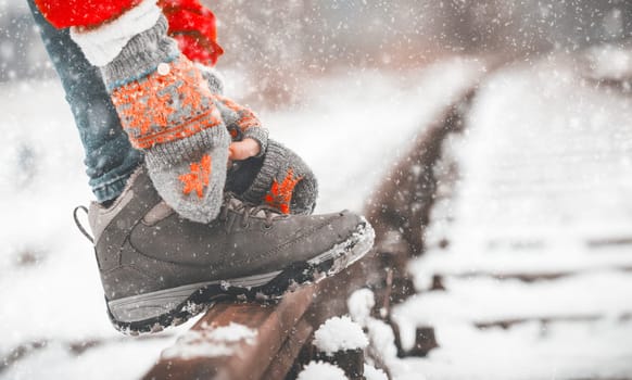 Girl tying shoe laces on the rails in winter