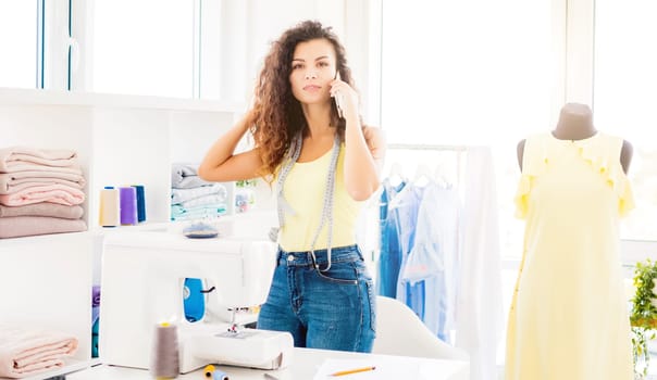 Professional tailor with phone in sewing atelier