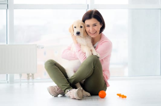 Beautiful woman hugging lovely young dog at home