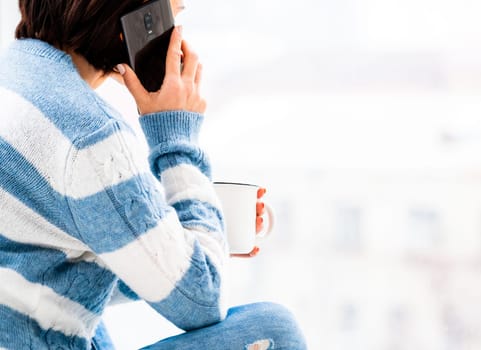 Girl talking on phone while drinking from cup