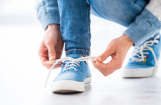 Person tying laces on gumshoes at home