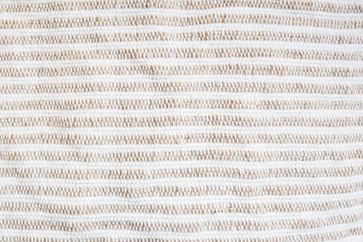 Beige-white striped background, rough fabric, close-up. Selective focus