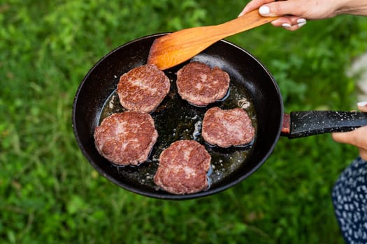 Fried patties in a pan. Rural menu. Traditional village food. Top view of a frying pan, a woman turns the patties with a spatula