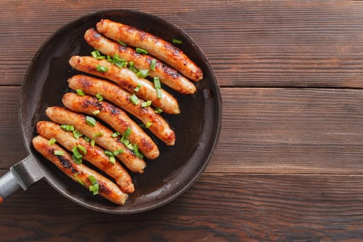 Delicious sausages cooked in a frying pan on a wooden table. copy space.