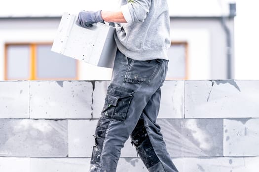 a mason builds the wall of a house from concrete blocks. High quality photo
