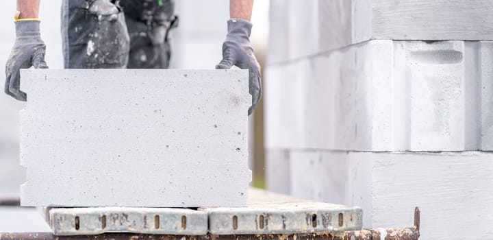 a mason builds the wall of a house from concrete blocks. High quality photo