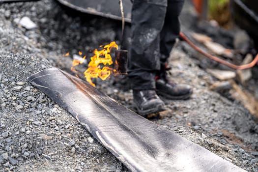 flame of fire from a gas burner to heat asphalt belts for building insulation.