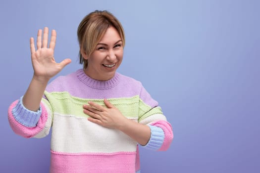 blond young woman in a striped sweater shows her palm on a blue background.