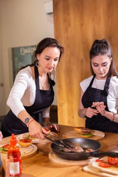 Preparing delicious burgers. Chef cooking meat burgers with beef, cheese and vegetables