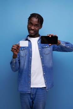 stylish american man with black dreadlocks holding money card mockup and smartphone.