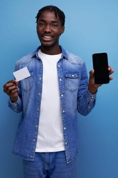 charismatic american man with black dreadlocks making payment with money card and smartphone.