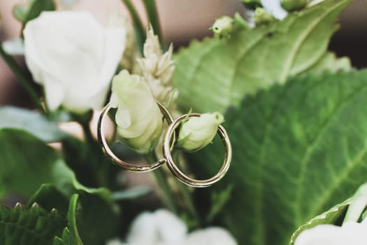 Wedding rings hang on a bridal bouquet