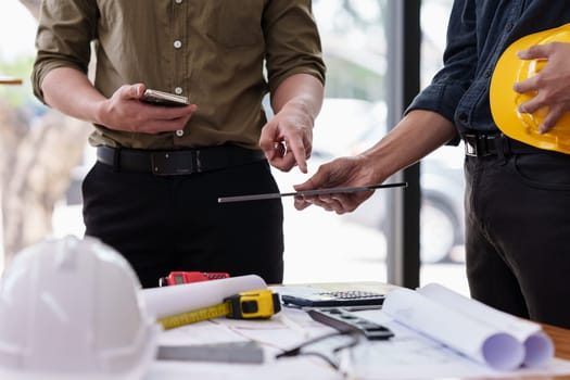 Architect and Engineer working with blueprints for architectural plan, engineer sketching a construction project, green energy concept.