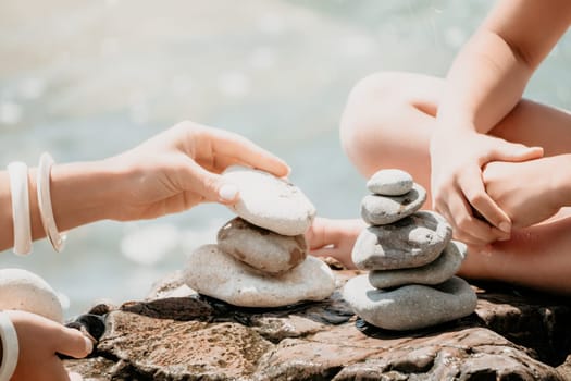 Balanced Pebbles Pyramid on the Beach on Sunny Day and Clear Sky at Sunset. Blue Sea on Background Selective focus, zen stones on sea beach, meditation, spa, harmony, calm, balance concept.