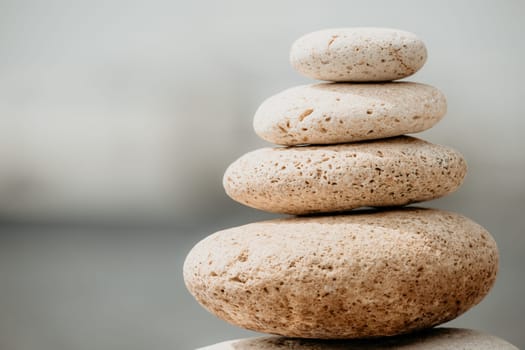 Pyramid stones on the seashore with warm sunset on the sea background. Happy holidays. Pebble beach, calm sea, travel destination. Concept of happy vacation on the sea, meditation, spa, calmness.